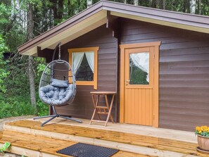 A wooden cabin with a porch, a hanging chair, a small table, and a door. - Joutsen by Interhome (Ruovesi)