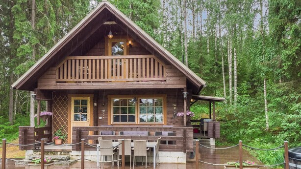A wooden cabin with a balcony, surrounded by a wooden deck and a rope barrier.