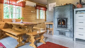 A cozy cabin interior with a stone fireplace, wooden benches, and a dining table.
