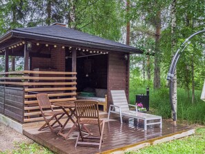 A wooden cabin with a deck, two wooden chairs, a white chair, and a small table. - Joutsen by Interhome (Ruovesi)