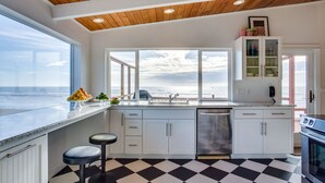 A kitchen with a view of the ocean, white cabinets, a black and white checkered floor, and a wooden ceiling. - Ocean Front Hot Tub, South Beach, Newport, Dog Friendly! (South Beach)