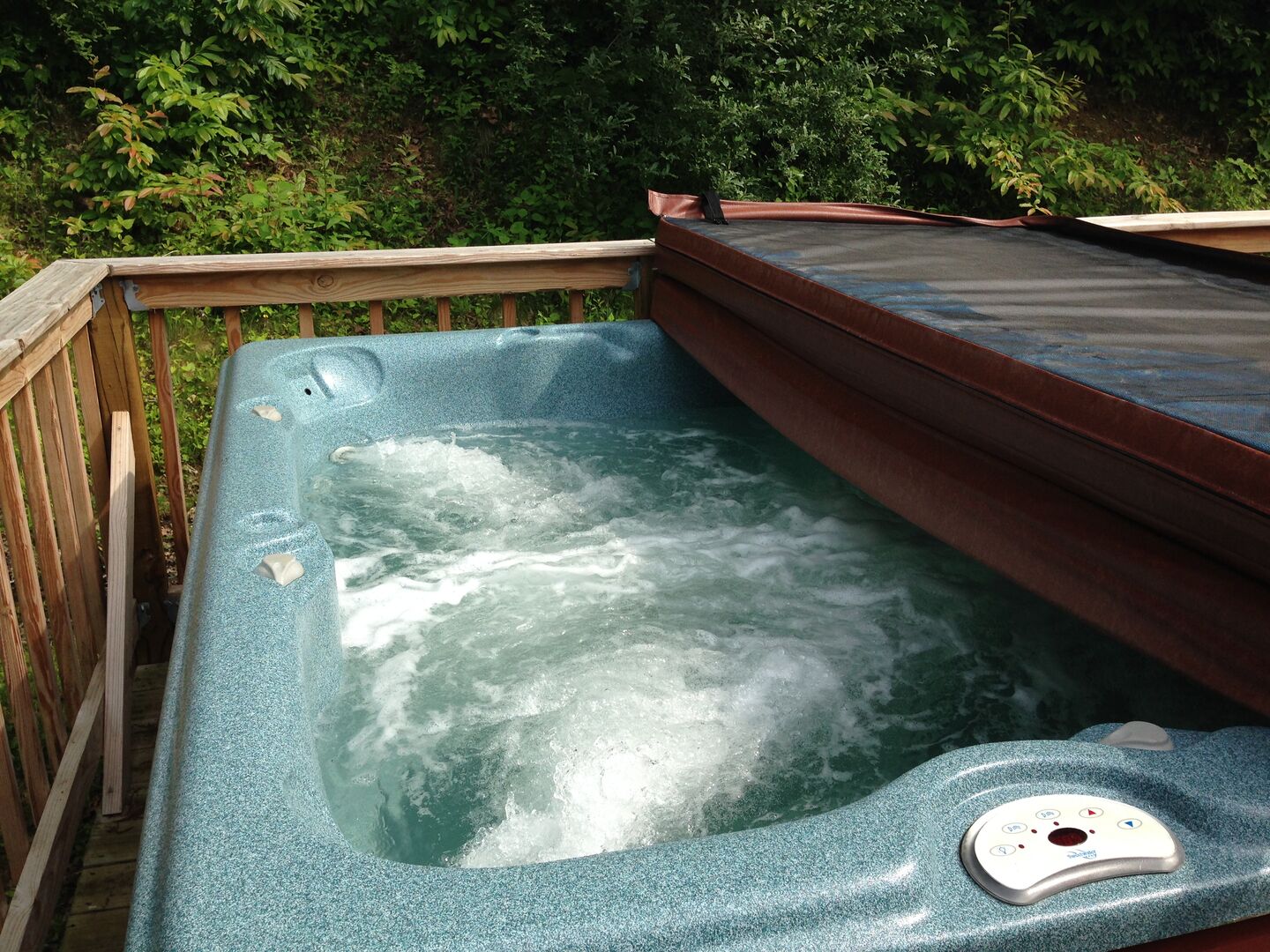 Ein Whirlpool mit Holzterrasse und Bedienfeld.