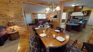 A cozy cabin interior with a dining area, a living room, and a kitchen.