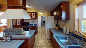 A compact kitchen with wooden cabinets, a stainless steel sink, and a microwave.