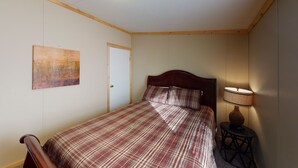 Un dormitorio con una cama, una puerta, una lámpara de pared y un cuadro.