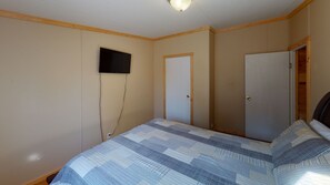 A bedroom with a bed, a television mounted on the wall, and two doors. - Large, Open Sunset Cabin in Star of Hocking Hills (Nelsonville)
