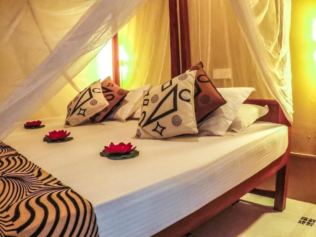 A bed with a canopy, multiple pillows with geometric patterns, and lotus flowers on the bed.