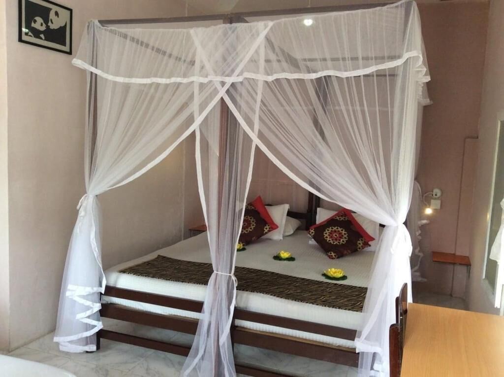 A bed with a canopy, pillows, and a small table.