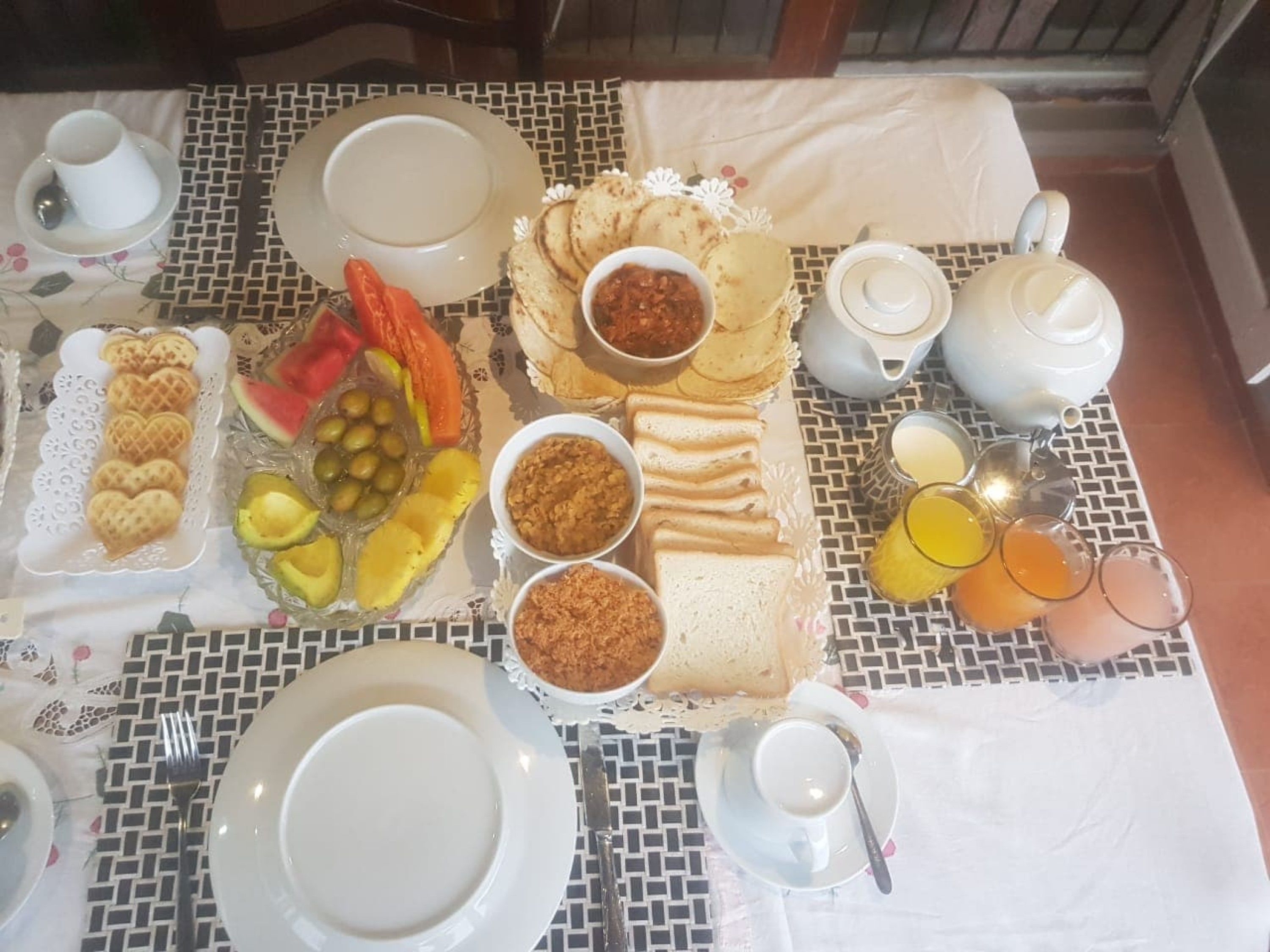 A breakfast table with plates, bowls, a teapot, and glasses.