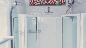 Un baño con un lavabo blanco, dos cabinas de ducha con mampara de vidrio y un adorno en la pared sobre el lavabo.