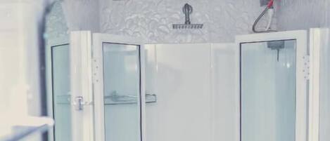 A bathroom with a white sink, two glass-enclosed shower stalls, and a decorative wall piece above the sink.