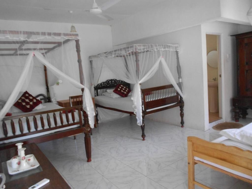 A room with two wooden beds, each with a canopy, a wooden table with a tray, and a wooden chair.