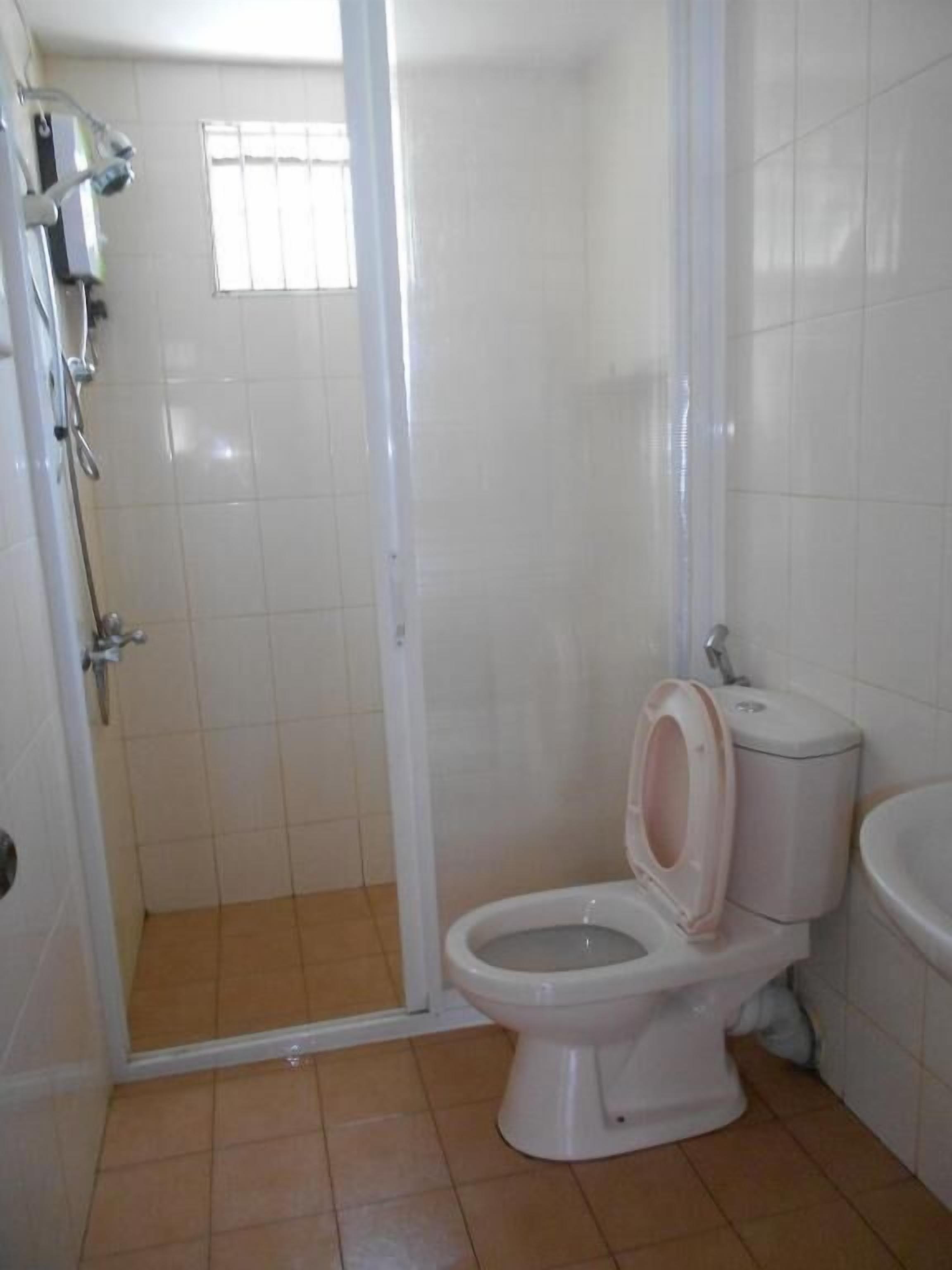 A bathroom with a toilet, a shower enclosure, and a sink.