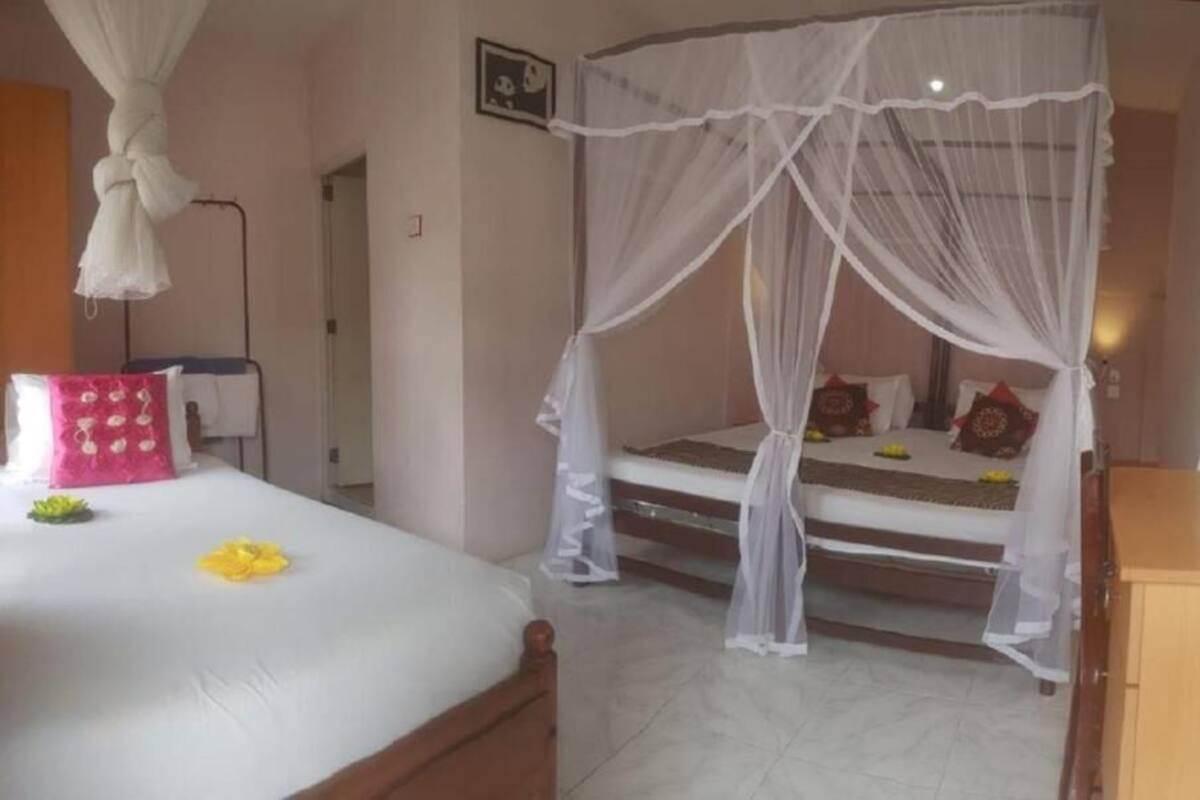 Een slaapkamer met een hemelbed, nachtkastje en een houten kast.