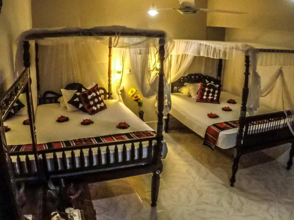 A room with two four-poster beds, each with a canopy, and a small table between them.