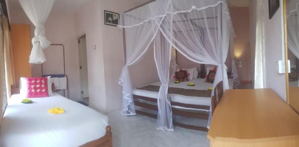 Een slaapkamer met een hemelbed, een nachtkastje en een houten bankje.