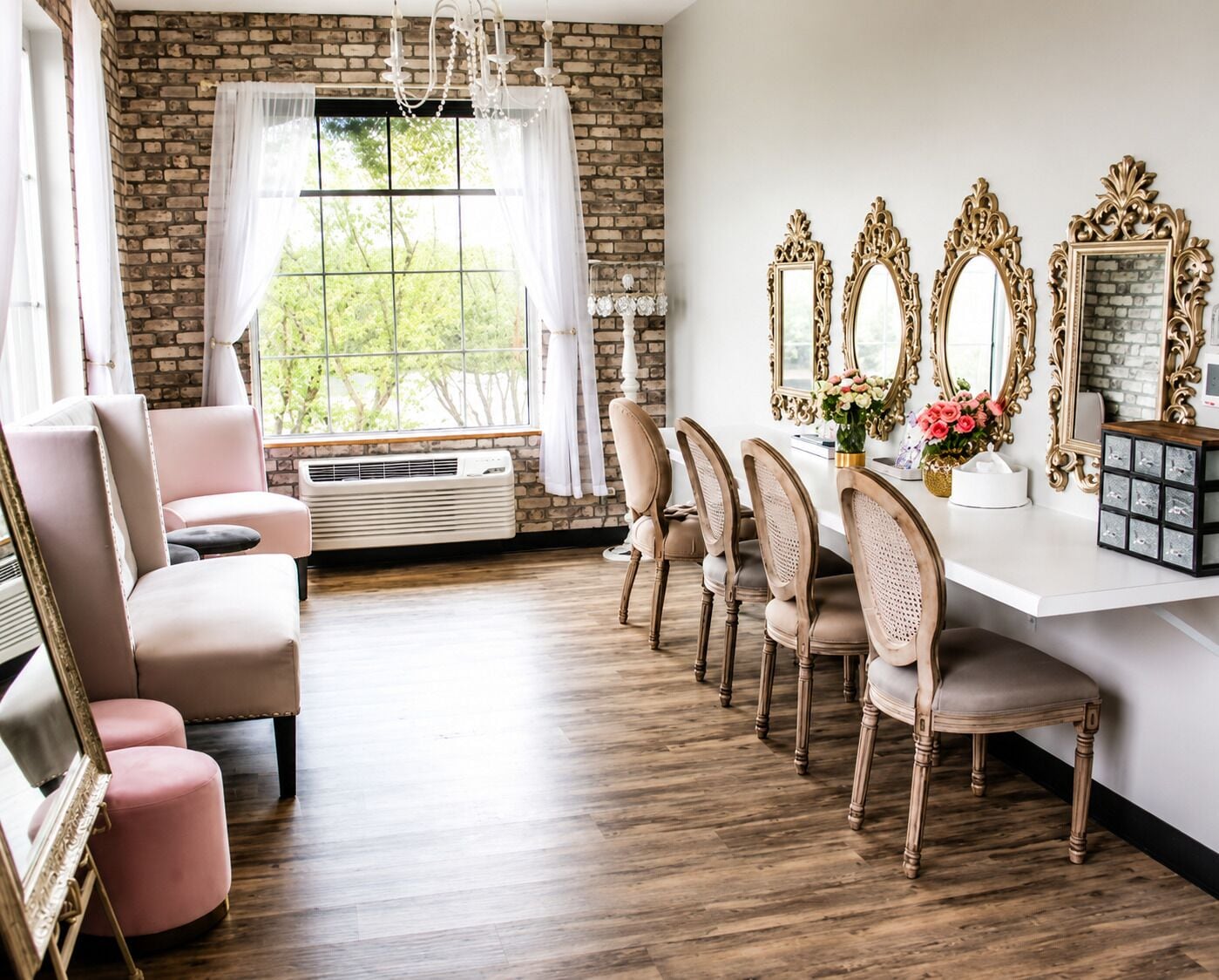 Un comedor con pared de ladrillo, un ventanal grande y una mesa blanca con espejos decorativos.