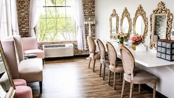 Un comedor con pared de ladrillo, un ventanal grande y una mesa blanca con espejos decorativos.