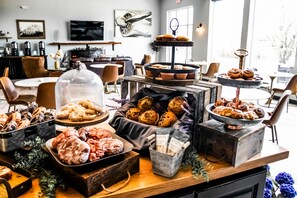 A buffet table with various pastries and desserts, a coffee station, and a seating area with chairs and tables.