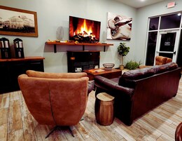 Una sala de estar con chimenea, sofás de cuero, una mesa de centro y un televisor.