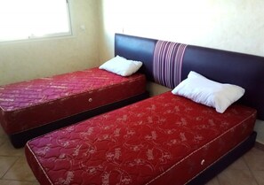 Two red mattresses with white pillows in a room with a plain wall and a window. - Residence Riviera Beach 4113 (Cabo Negro)