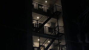 Ein mehrstöckiges Gebäude mit einer gut sichtbaren, beleuchteten Werbetafel, einer Treppe und einem verschlossenen Eingang.