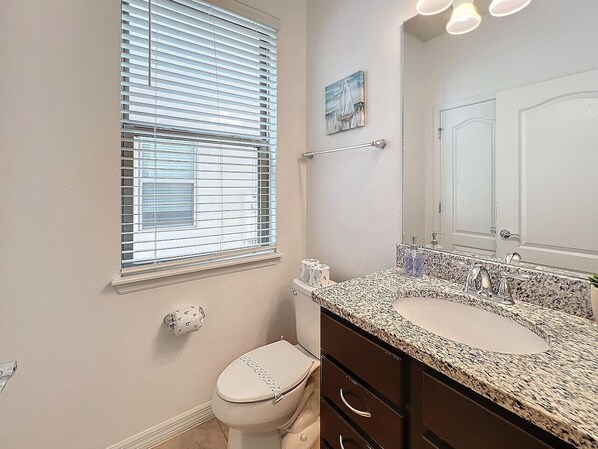 A bathroom with a toilet, sink, and mirror.