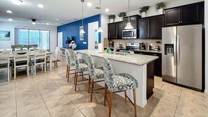 A modern kitchen with dark cabinets, stainless steel appliances, and a central island with bar stools.