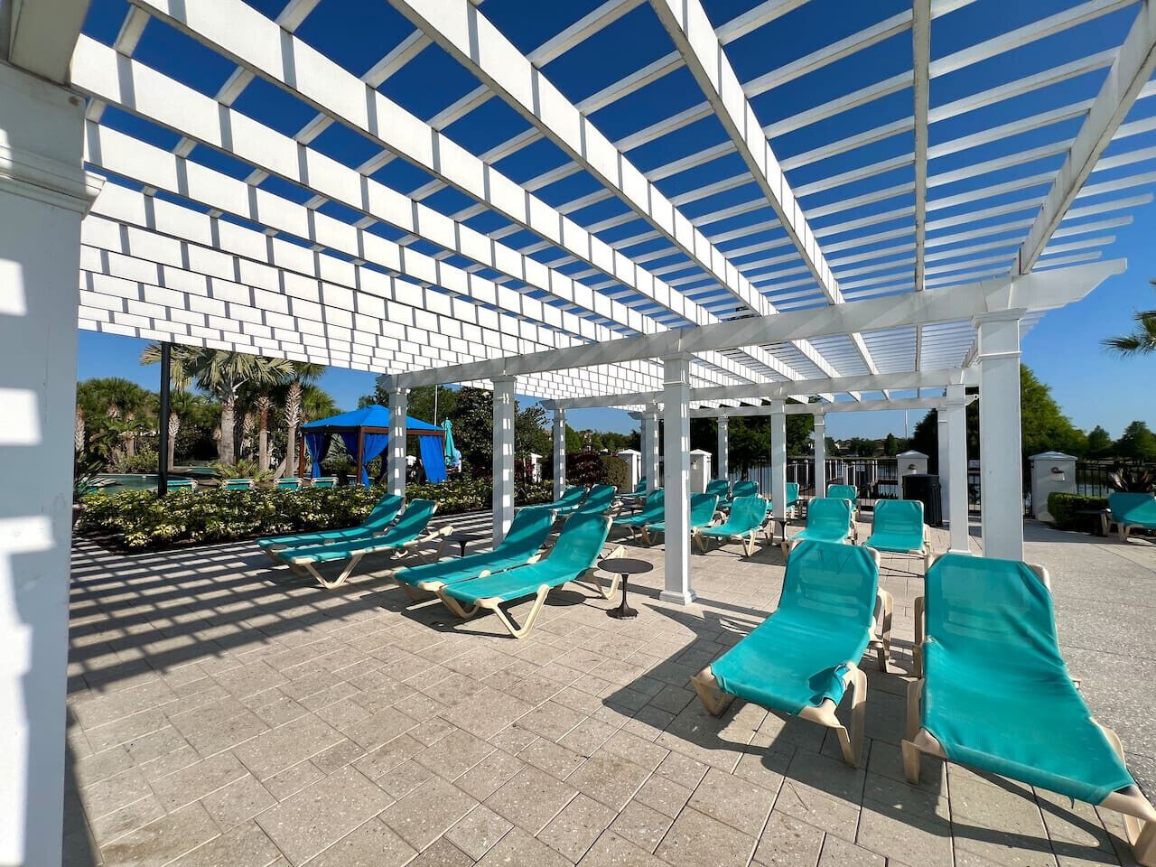 Een overdekt terras met meerdere lounge stoelen en een blauw zonnescherm.