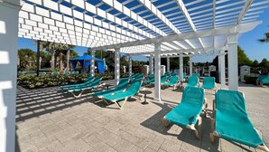 A covered outdoor area with multiple lounge chairs and a blue canopy structure.