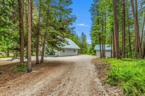 A gravel driveway leading to a house surrounded by tall trees. - Sugar Shack - Peaceful and Private Remodeled Cabin (Leavenworth)