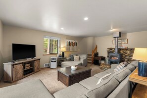 A living room with a TV, sofa, fireplace, and a stone wall. - Sugar Shack - Peaceful and Private Remodeled Cabin (Leavenworth)