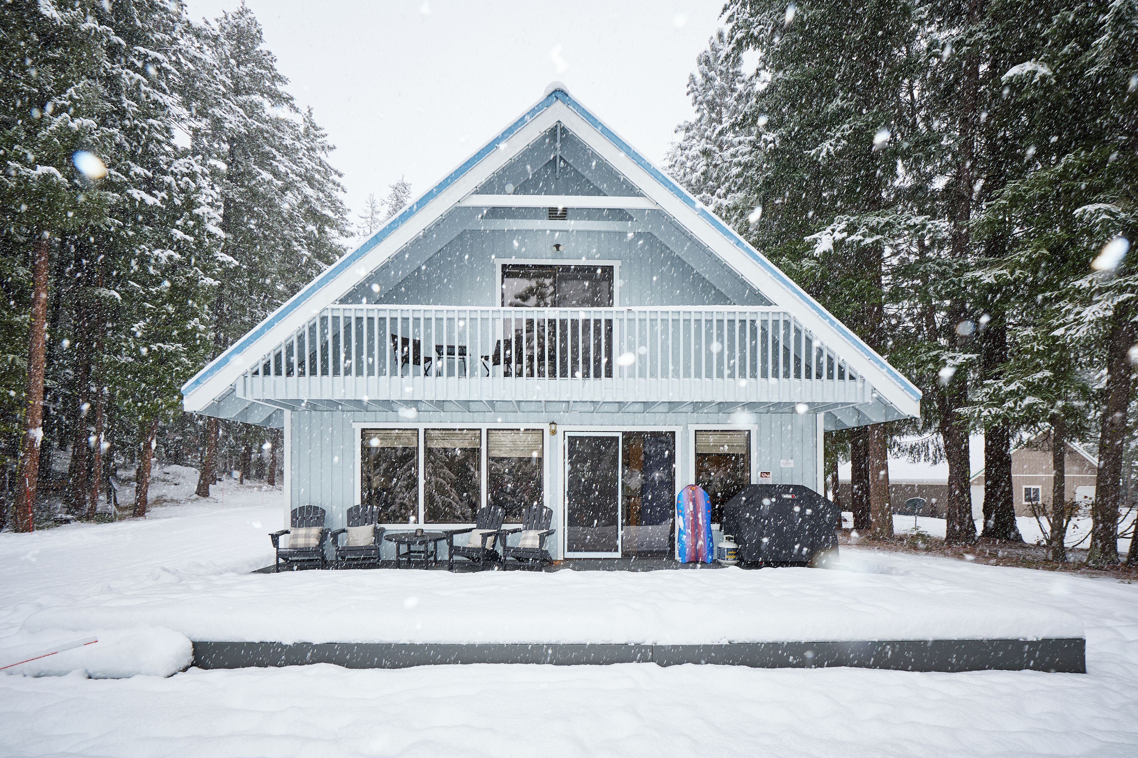 A two-story house with a balcony, surrounded by snow-covered trees.
