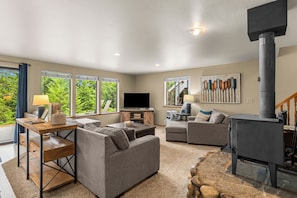 A living room with a fireplace, sofas, a TV, and large windows.