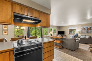 A modern kitchen with wooden cabinets, a built-in stove, and a dining area with a table and chairs.