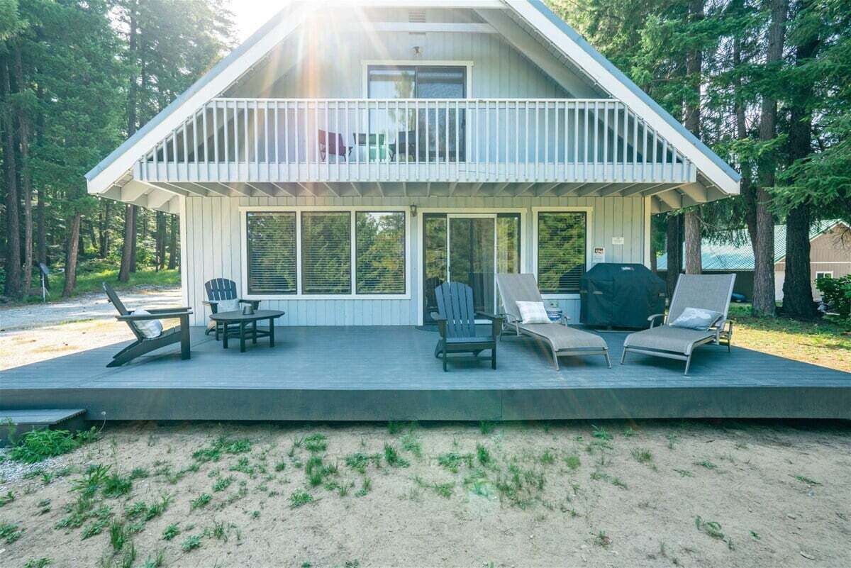 A two-story house with a balcony, outdoor seating, and a grill.