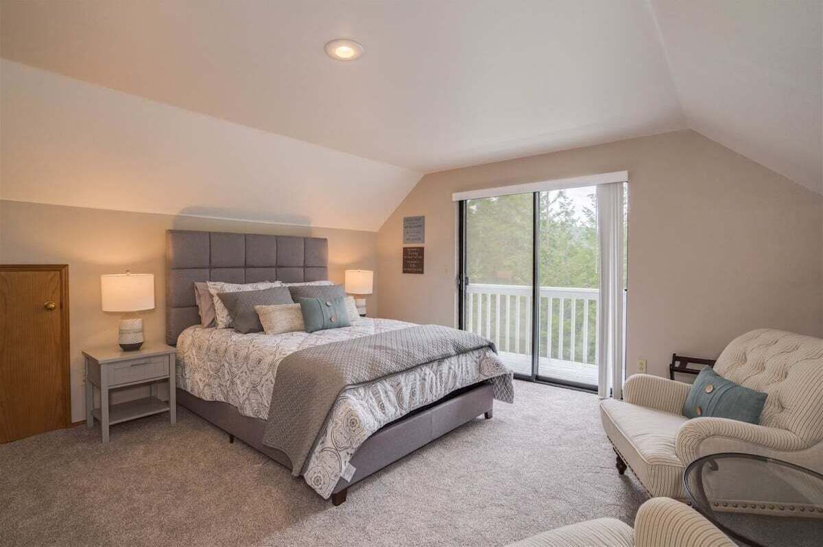 A bedroom with a bed, nightstands, a chair, and a balcony.