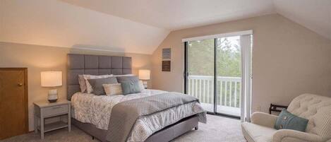 A bedroom with a bed, nightstands, a chair, and a balcony.