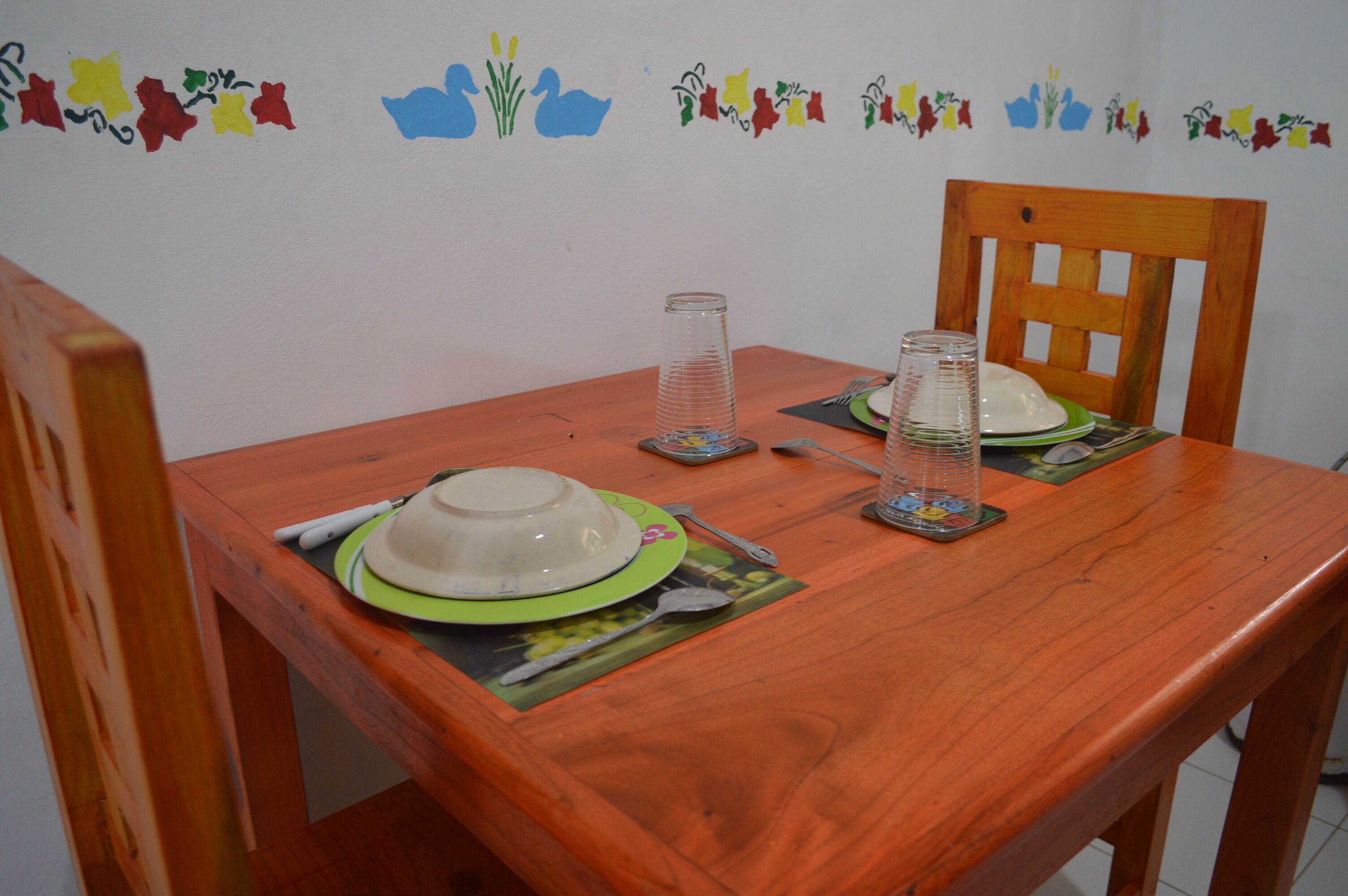 Une table de salle à manger en bois, avec deux assiettes, un verre et une cuillère.