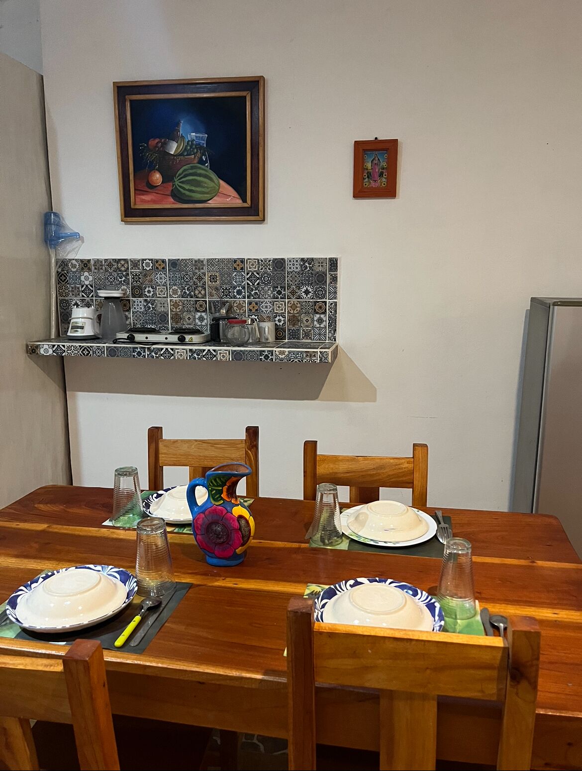 A dining table set with plates, a pitcher, and a coffee maker.