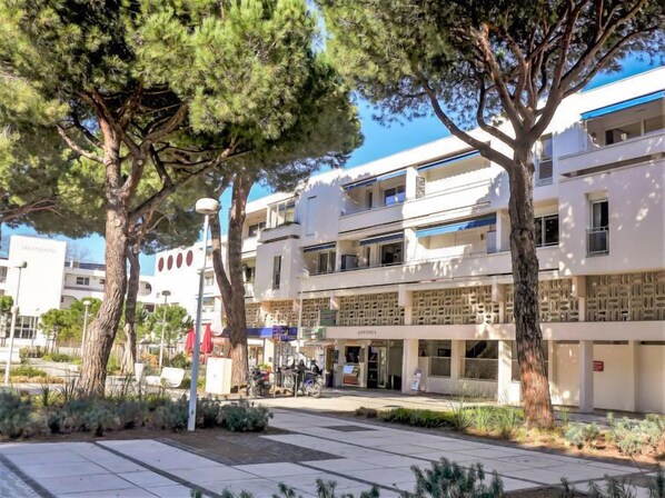 A modern building with a flat roof, multiple balconies, and a ground floor with shops.