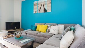 A modern living room with a grey sofa, a coffee table, and a flat-screen TV.