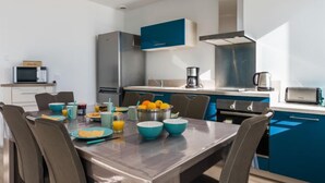 A modern kitchen with a dining table, chairs, and various kitchen appliances.