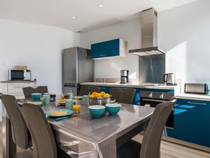 A modern kitchen with a dining table, chairs, and various kitchen appliances.