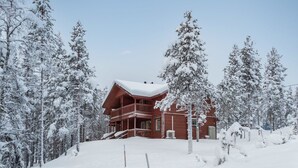 Un gran albergue de madera con balcón, rodeado de árboles cubiertos de nieve.