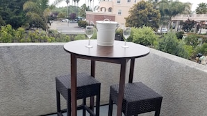 A round table with two wicker chairs and two wine glasses on a balcony with a view of a residential area. - Ocean-View 2 Bedroom Home Sleeps 6 Steps From Beach & Train Station, Pets OK (Grover Beach)