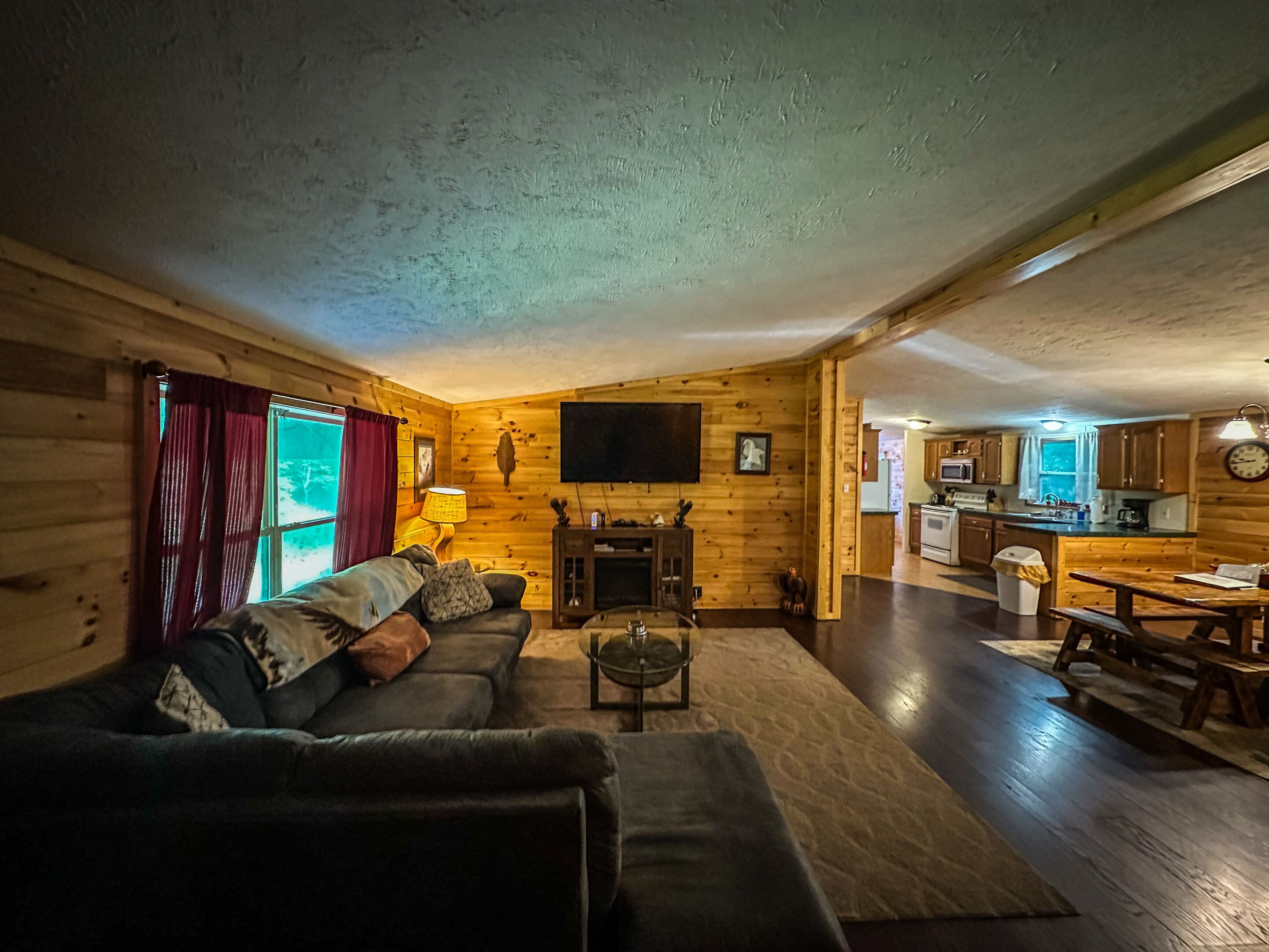 Interior acogedor de una cabaña de madera con sala de estar, comedor y cocina.