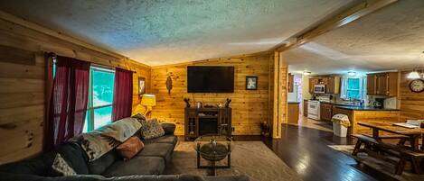 Interior acogedor de una cabaña de madera con sala de estar, comedor y cocina.