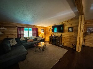 A cozy cabin-style room with a sectional sofa, a flat-screen TV, and a wooden entertainment unit.