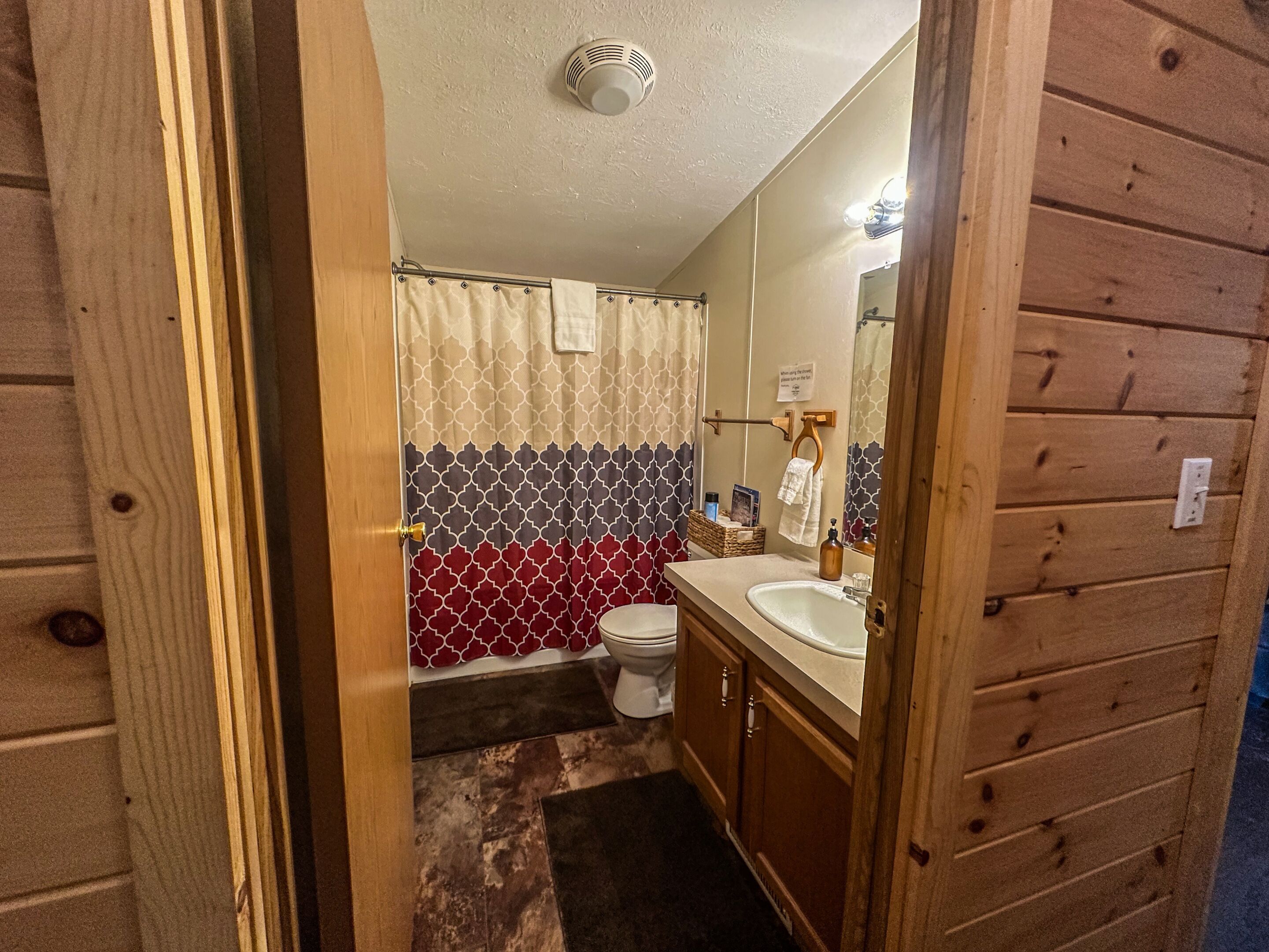 Un baño con paneles de madera, un inodoro, un lavabo y cabina de ducha.